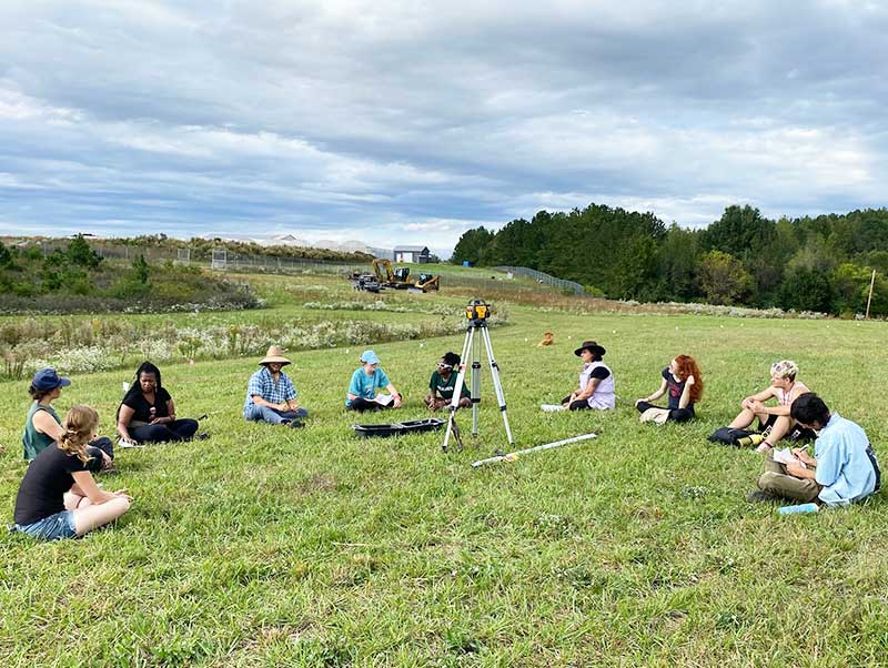 Students learning in a field setting sitting in a circle.